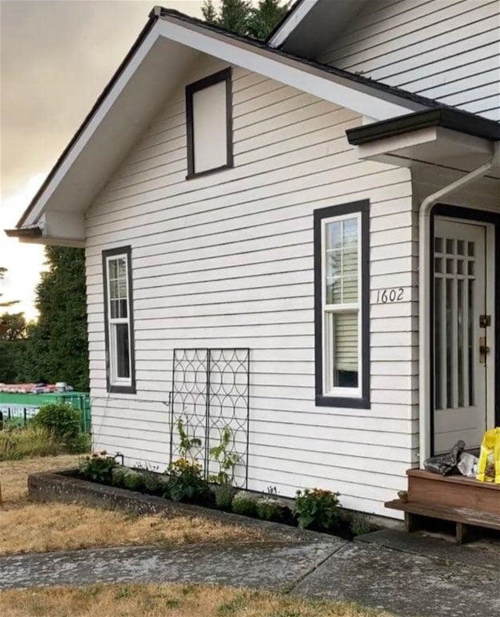 Before: farmhouse entry with horizontal siding and dark window trim